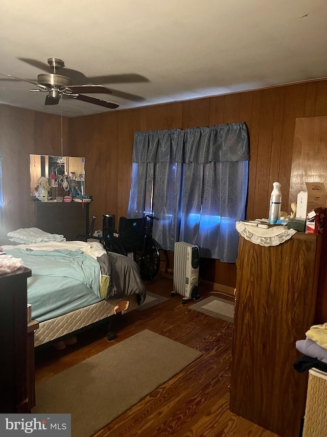 bedroom with wood walls, ceiling fan, and dark hardwood / wood-style floors