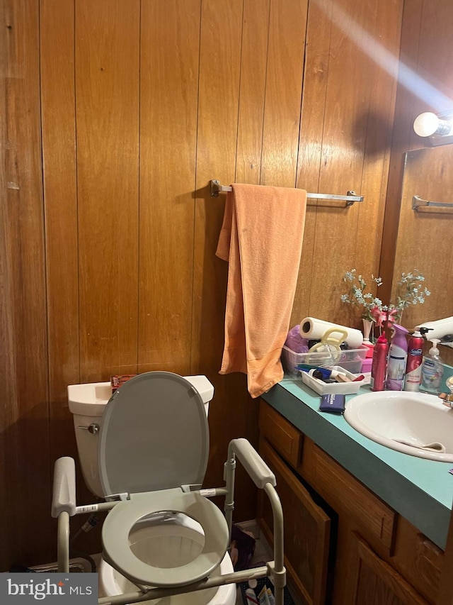 bathroom featuring toilet, wooden walls, and vanity