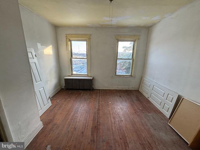 unfurnished room with radiator, dark hardwood / wood-style flooring, and a healthy amount of sunlight