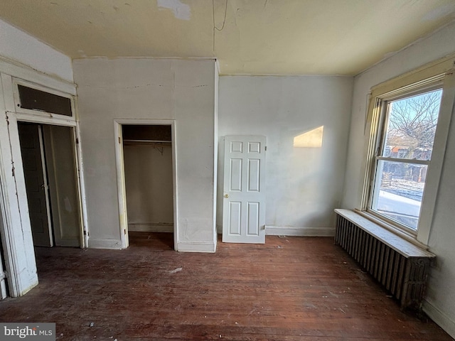 unfurnished bedroom featuring radiator heating unit and dark hardwood / wood-style floors