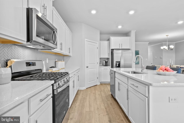 kitchen with stainless steel appliances, sink, white cabinetry, a chandelier, and a kitchen island with sink