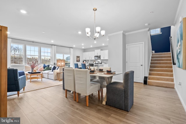 dining space featuring an inviting chandelier, ornamental molding, and light hardwood / wood-style flooring