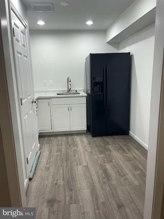 kitchen with white cabinetry, sink, black refrigerator with ice dispenser, and dark hardwood / wood-style flooring