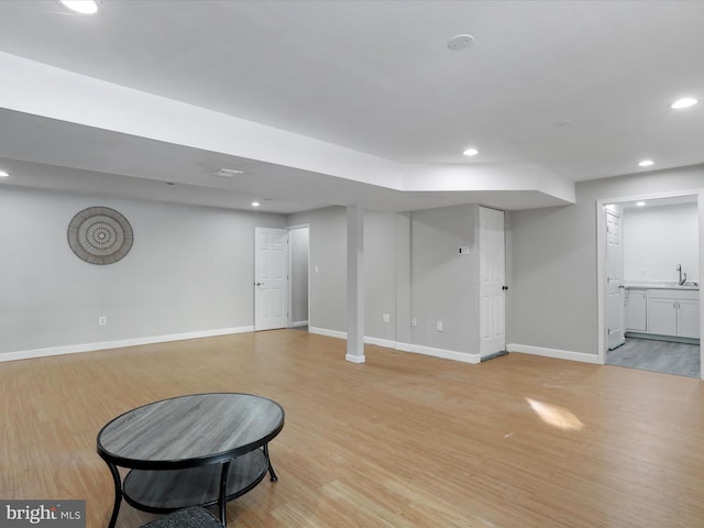 basement featuring sink and light hardwood / wood-style floors