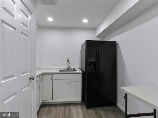 kitchen featuring dark wood-type flooring, black fridge with ice dispenser, sink, and white cabinets