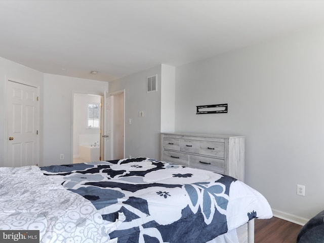 bedroom featuring dark wood-type flooring and ensuite bath