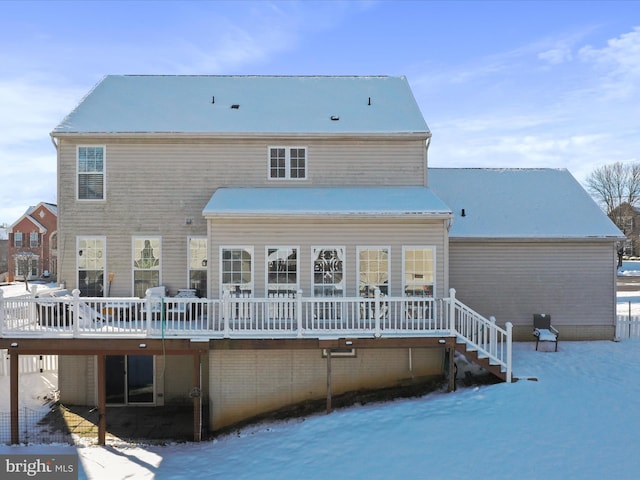 snow covered back of property featuring a wooden deck