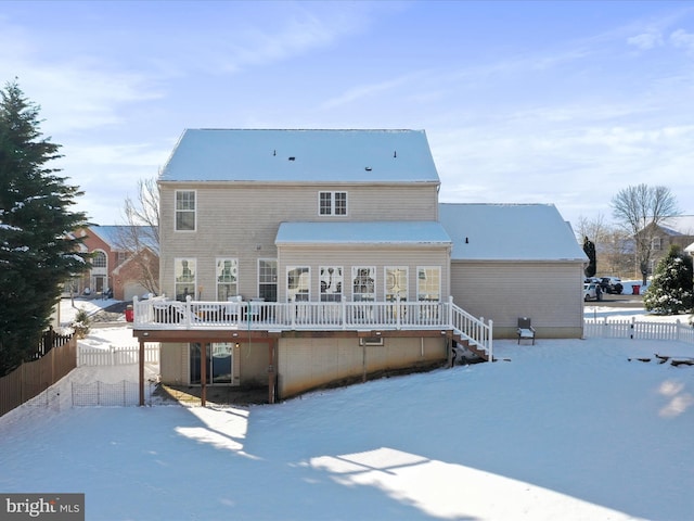 snow covered rear of property with a deck