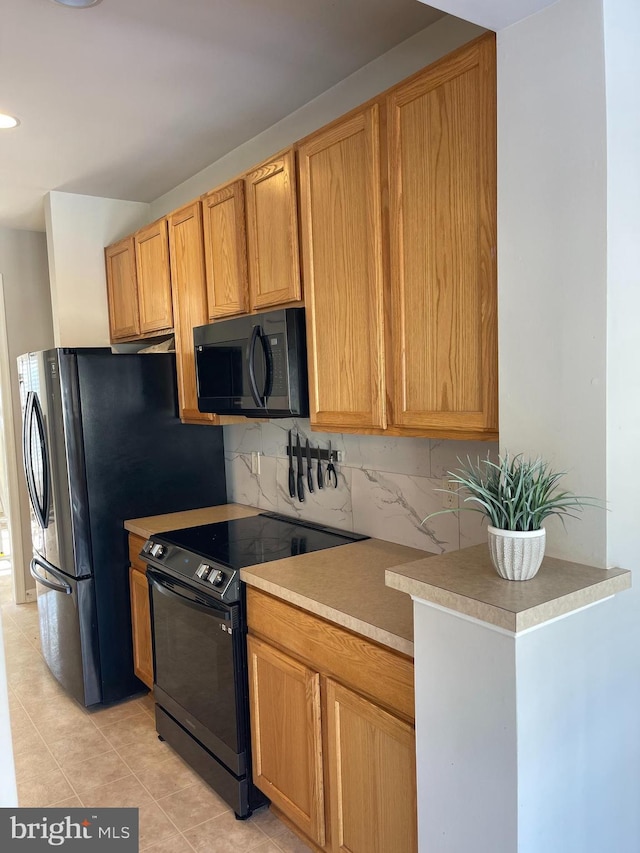 kitchen featuring light tile patterned floors, decorative backsplash, and black appliances