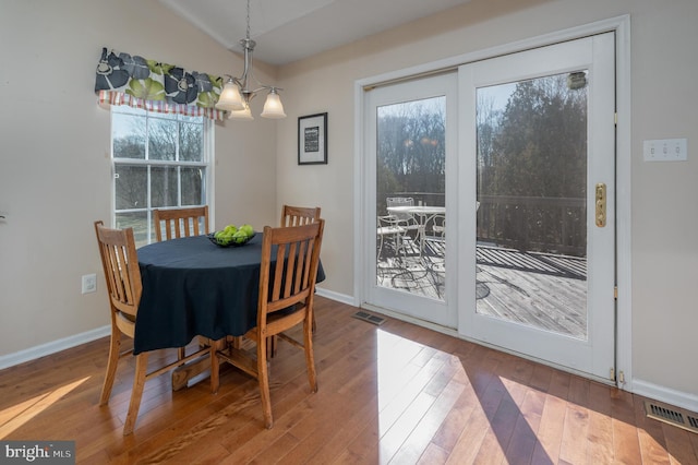 dining space featuring hardwood / wood-style flooring, vaulted ceiling, a chandelier, and plenty of natural light