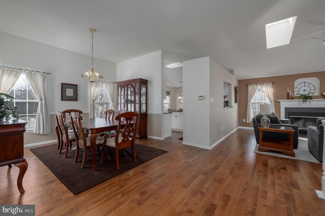 dining space featuring ceiling fan with notable chandelier, a healthy amount of sunlight, and wood-type flooring