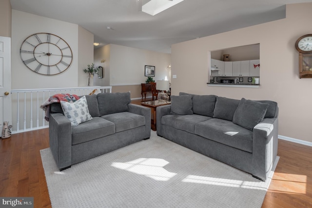 living room featuring light hardwood / wood-style floors and a skylight