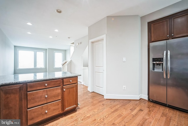 kitchen featuring light stone counters, light hardwood / wood-style flooring, and stainless steel fridge