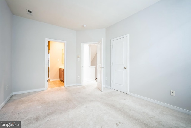 unfurnished bedroom with light colored carpet and ensuite bathroom