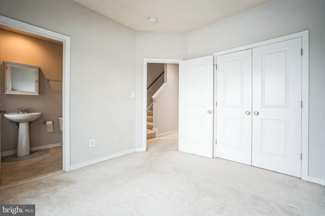 unfurnished bedroom featuring ensuite bath and light carpet