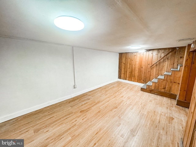 basement with wooden walls and light hardwood / wood-style flooring