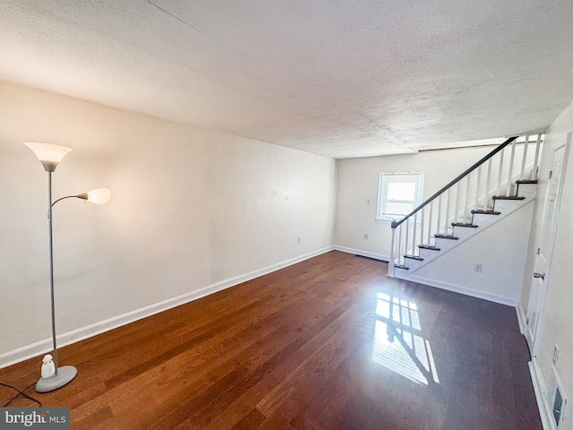 interior space featuring a textured ceiling and dark wood-type flooring