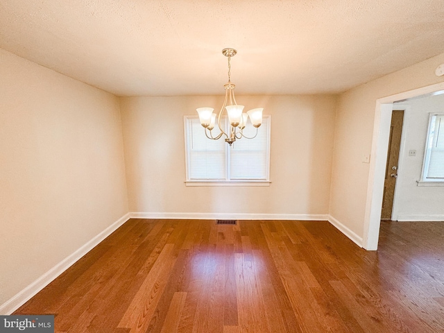 empty room featuring a chandelier and dark hardwood / wood-style floors