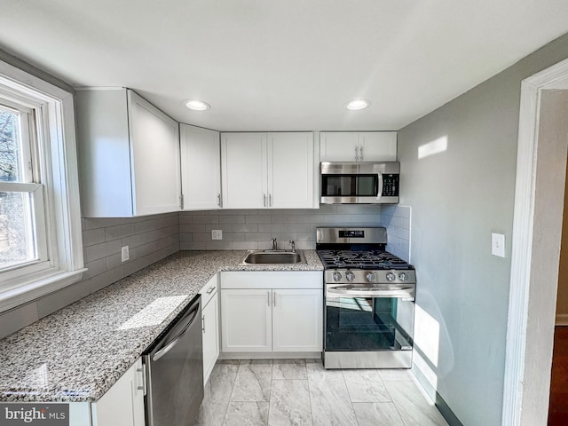 kitchen featuring sink, stainless steel appliances, white cabinetry, and tasteful backsplash