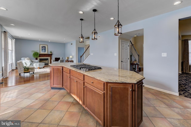 kitchen featuring light stone counters, light tile patterned floors, decorative light fixtures, and a center island