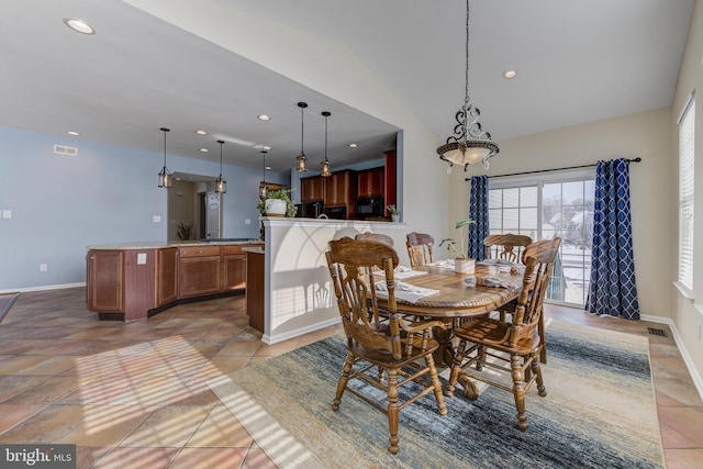 tiled dining room featuring vaulted ceiling