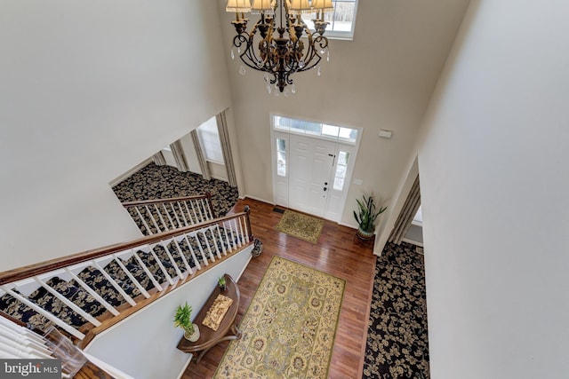 entrance foyer with a towering ceiling, wood-type flooring, and a chandelier