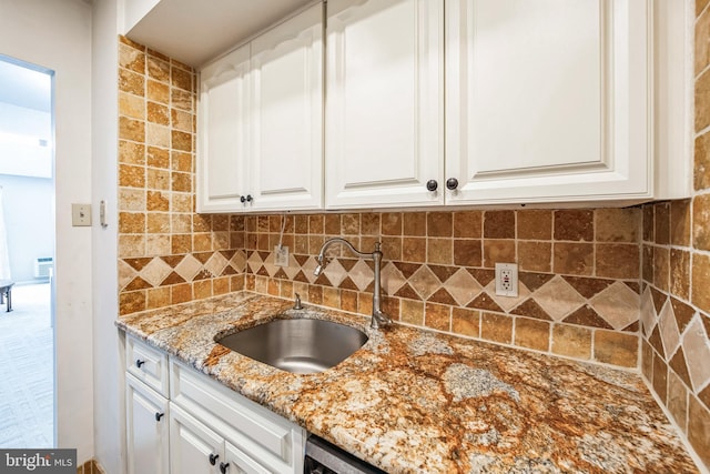 kitchen featuring light stone countertops, decorative backsplash, white cabinets, and sink