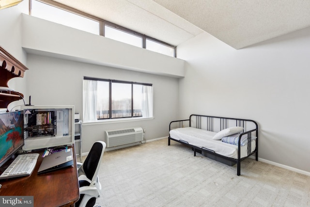 office space with a high ceiling, light colored carpet, a textured ceiling, and a wall mounted AC