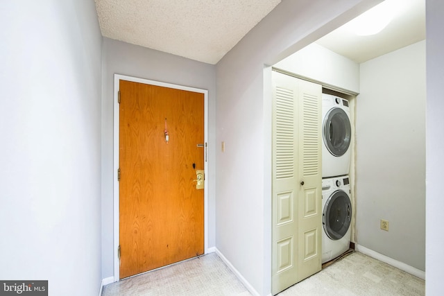 laundry room with a textured ceiling and stacked washer / drying machine