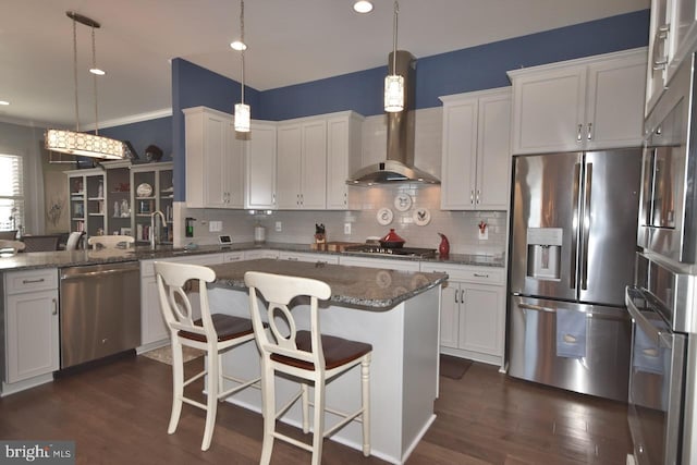 kitchen with appliances with stainless steel finishes, white cabinets, decorative light fixtures, and a breakfast bar area