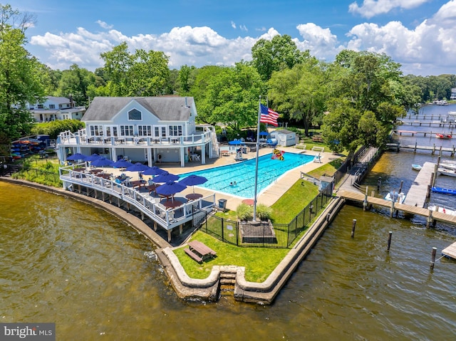 rear view of property featuring a fenced in pool, fence private yard, a deck with water view, and a yard