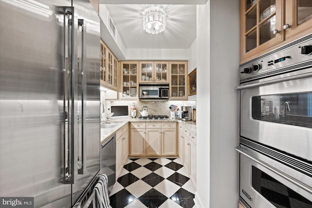 kitchen featuring appliances with stainless steel finishes, light brown cabinetry, tasteful backsplash, sink, and light stone countertops