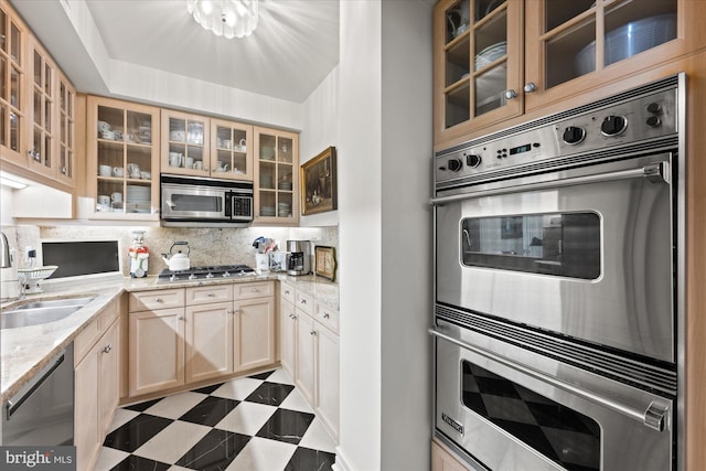 kitchen featuring sink, light brown cabinets, stainless steel appliances, light stone countertops, and backsplash