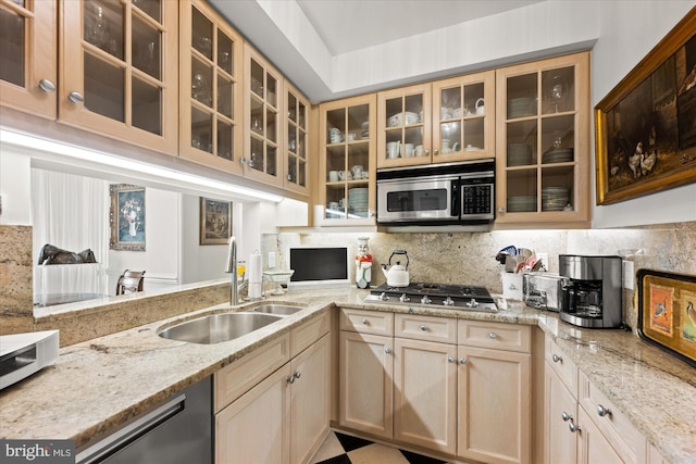 kitchen with light stone counters, sink, decorative backsplash, and appliances with stainless steel finishes