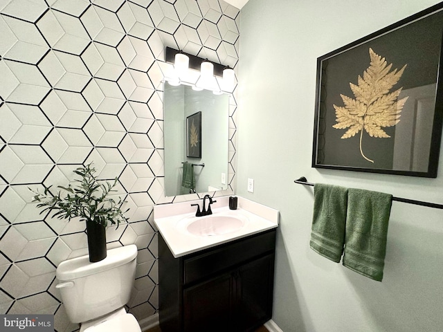 bathroom featuring toilet, vanity, and tile walls