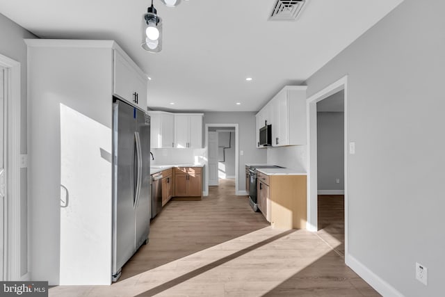 kitchen with white cabinetry, pendant lighting, light hardwood / wood-style floors, and appliances with stainless steel finishes