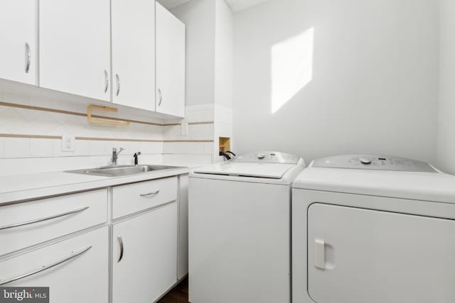 clothes washing area with sink, cabinets, and independent washer and dryer