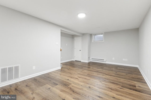 basement featuring hardwood / wood-style floors and a baseboard heating unit