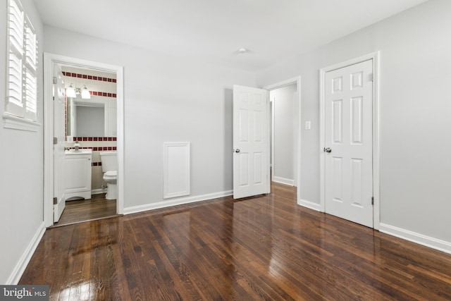 unfurnished bedroom with dark wood-type flooring and connected bathroom