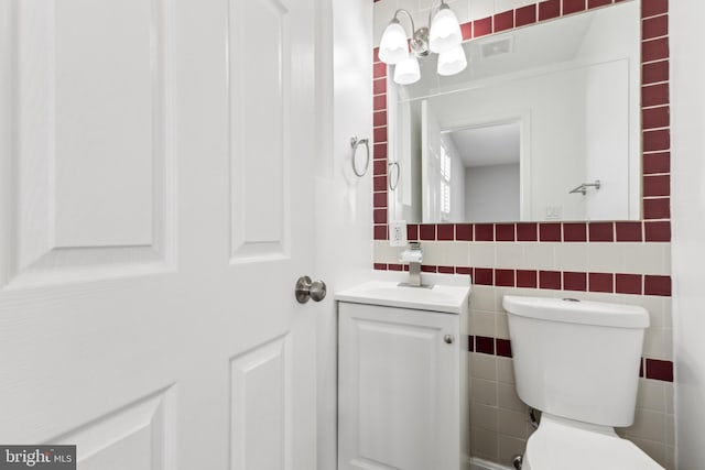 bathroom featuring tile walls, vanity, and toilet