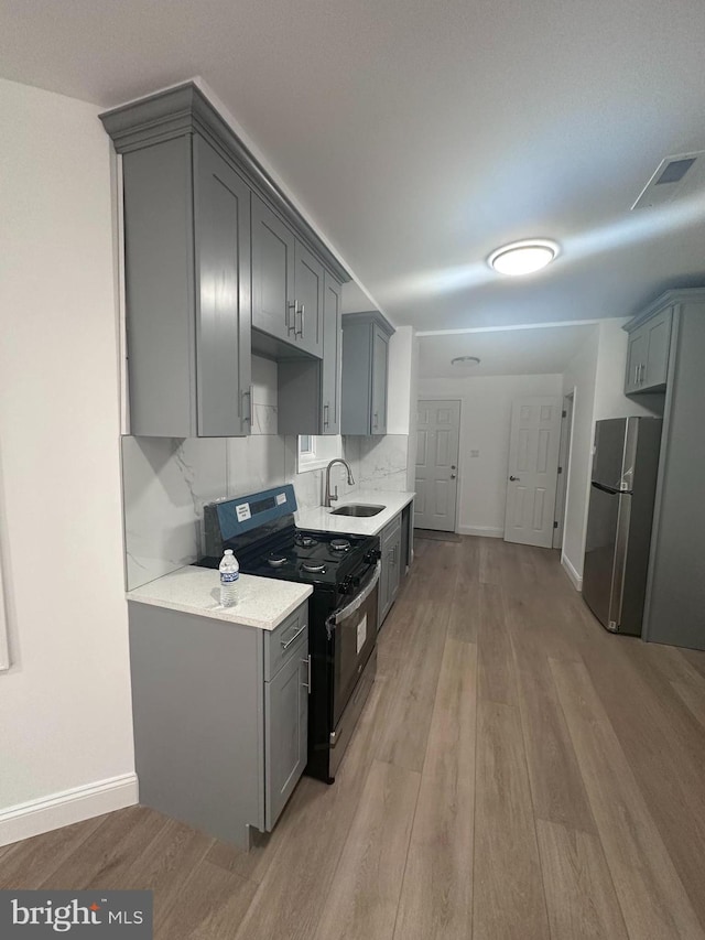 kitchen with gray cabinets, black electric range, tasteful backsplash, stainless steel refrigerator, and sink