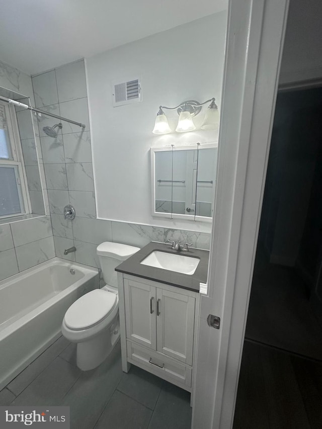 full bathroom with toilet, tiled shower / bath combo, tile patterned floors, and vanity