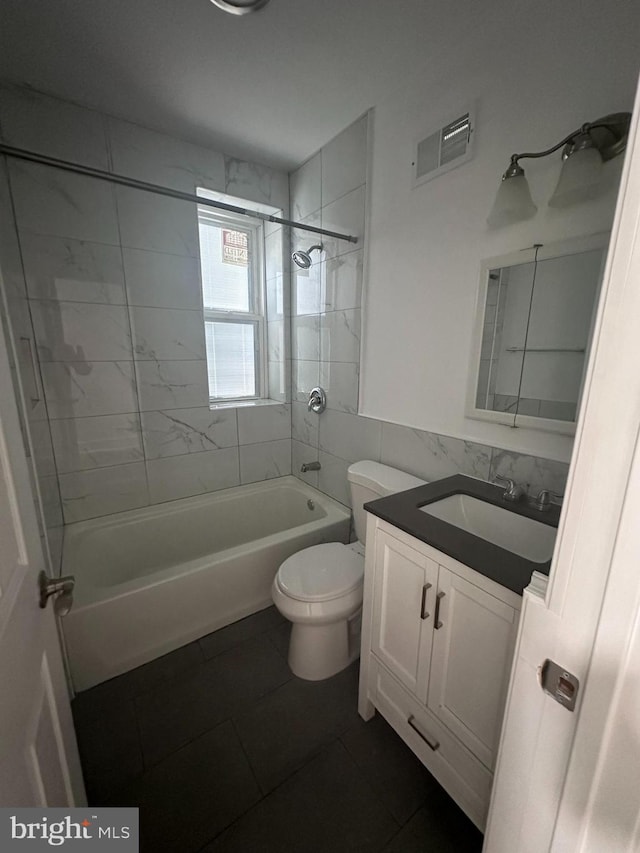 full bathroom with toilet, vanity, tile walls, tile patterned floors, and tiled shower / bath combo