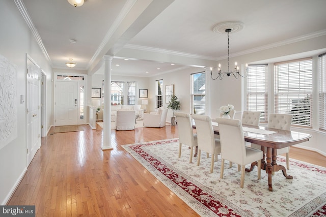 dining room with ornamental molding, decorative columns, light hardwood / wood-style flooring, and a notable chandelier