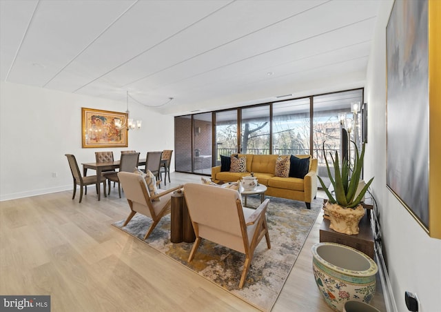 living room with floor to ceiling windows, a chandelier, and light wood-type flooring