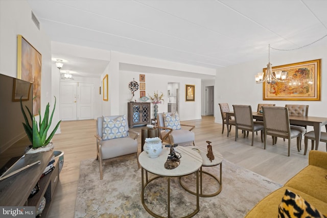 living room featuring light hardwood / wood-style flooring and an inviting chandelier