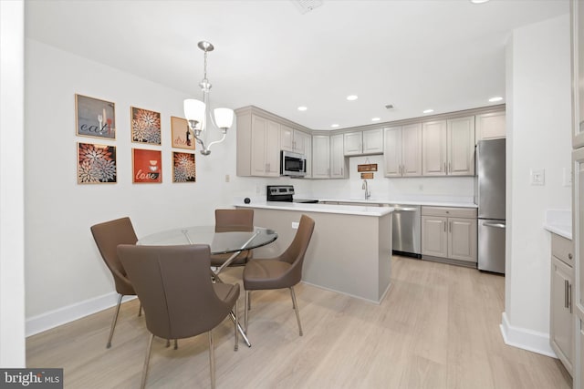 kitchen with a notable chandelier, light hardwood / wood-style floors, sink, hanging light fixtures, and stainless steel appliances