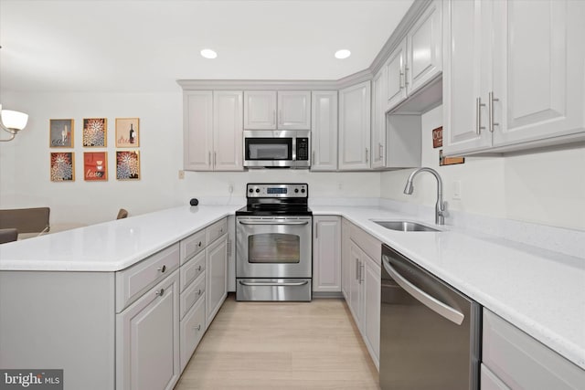 kitchen featuring stainless steel appliances, pendant lighting, kitchen peninsula, and sink