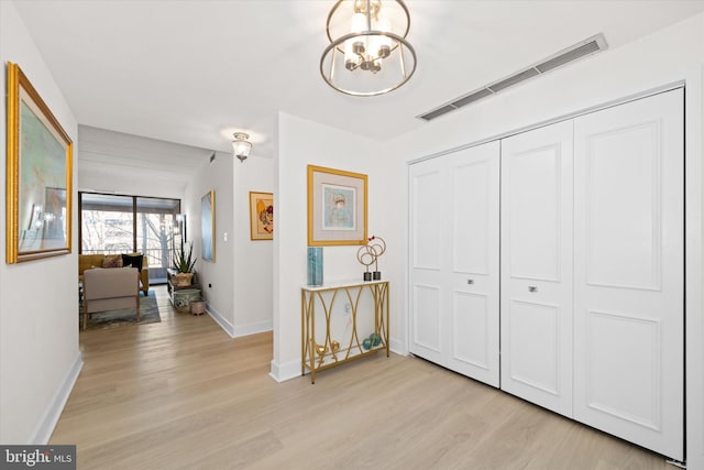 hall featuring an inviting chandelier and light hardwood / wood-style flooring