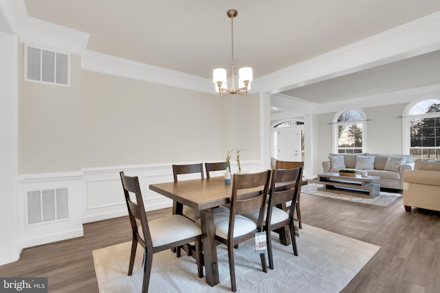 dining area featuring dark wood-type flooring, ornamental molding, and a chandelier